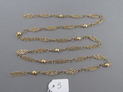 trois colliers à chaîne dorée et une étiquette posée sur une surface grise