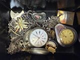 a pile of assorted watches and other items on a black surface