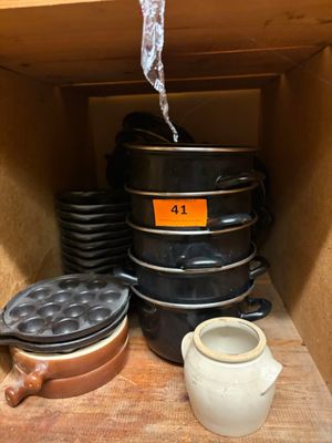Plusieurs casseroles et poêles sont empilées sur une étagère dans une cuisine