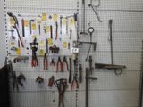 de nombreux outils accrochés à un panneau perforé dans un garage