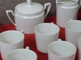 many cups and saucers sitting on a red table