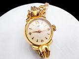 a gold watch with a chain around it sitting on a white surface