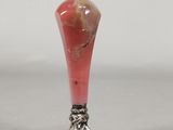 a small red vase with a silver base on a table