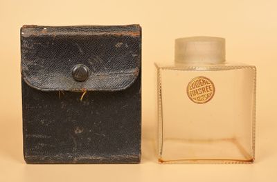 une vieille bouteille d'eau de Cologne posée à côté d'un petit étui sur une table