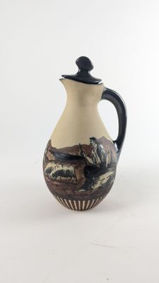 a small pitcher with a painting on it sitting on a table