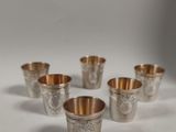 six coupes en argent ornées de motifs, posées sur une surface blanche