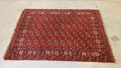 Le tapis posé au sol est rouge et marron, avec un motif.