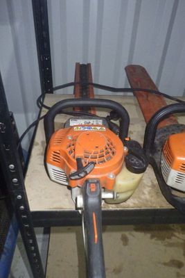 deux tronçonneuses posées sur une étagère dans un garage