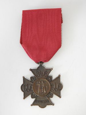une ancienne médaille avec un ruban rouge sur fond blanc