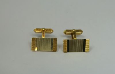 a pair of gold cufflinks on a white surface
