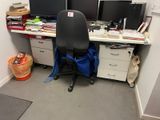 un bureau avec deux écrans d'ordinateur et une chaise dans un coin