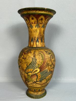 un vase jaune orné d'un oiseau, posé sur une table