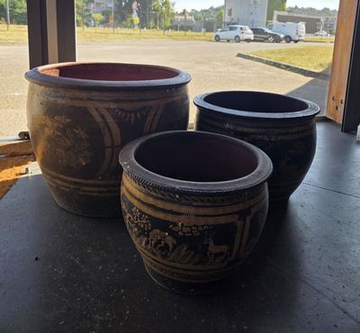 trois grands pots posés sur une table devant une fenêtre