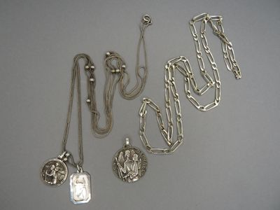 plusieurs colliers et pendentifs en argent posés sur un fond blanc