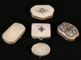 four pieces of carved ivory and silver jewelry on a black surface