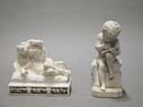 two white statues of a boy and a dog on a table