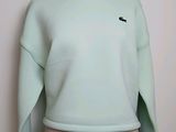 le dos d'un sweat-shirt vert sur lequel est brodé un oiseau noir