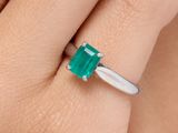 un gros plan sur la main d'une femme tenant une bague en émeraude