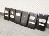 several cell phones are lined up against a wall in a row