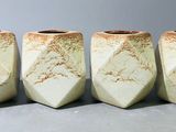 quatre vases blancs posés les uns à côté des autres sur une table