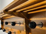 a close up of a wooden coat rack with black knobs