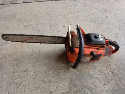 an orange chainsaw sitting on the ground in front of a building