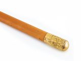 a close up of a wooden stick with a gold colored handle