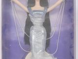 poupée dans la boîte d'une poupée Barbie, vêtue d'une robe et portant des perles