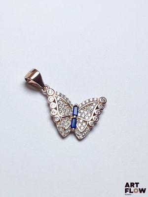 pendentif papillon orné de cristaux bleus et blancs sur fond blanc