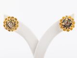 une paire de boucles d'oreilles en diamants jaunes et blancs, présentées sur un socle blanc
