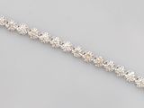 a close up of a diamond bracelet on a gray surface