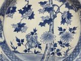 a blue and white plate with a bird and flowers on it
