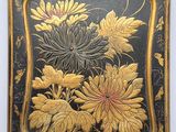 une boîte ancienne peinte en noir et or, ornée de fleurs