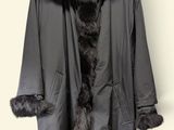 grey coat with black fur collar on hanger against white wall