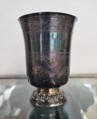 un vase en argent posé sur une table en verre