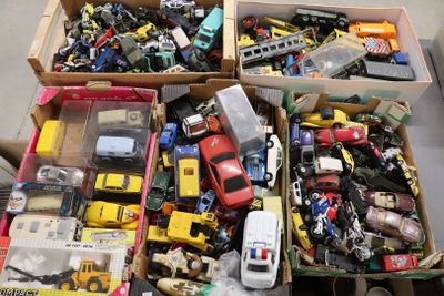 Des cartons remplis de petites voitures et de camions de toutes sortes sont posés par terre