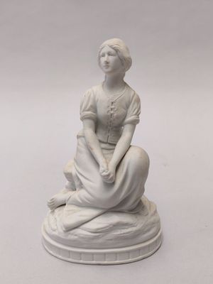 une statue blanche représentant une femme assise sur un socle