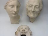 three heads of people on display on a white surface