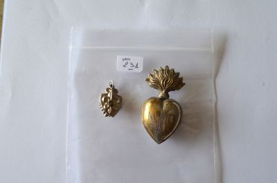 une broche en or et une paire de boucles d'oreilles posées sur une surface blanche