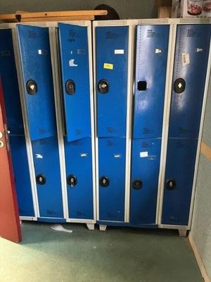 several blue lockers are lined up in a room with a red door