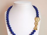 un gros plan d'un collier sur un mannequin, orné de perles bleues
