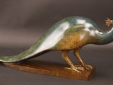 statue d'un paon posée sur un socle en bois, sur fond gris
