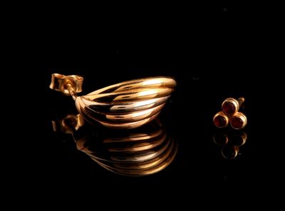 deux bagues en or et une paire de boucles d'oreilles posées sur une surface noire