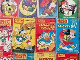 many mickey mouse books are stacked on the floor