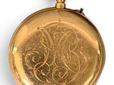 an old gold pocket watch with a monogram on the dial