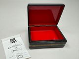 a small black box with a red lid and a certificate in it
