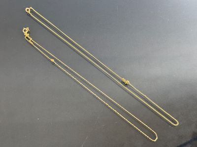 two gold chains on a black surface
