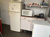 a small kitchen with a refrigerator, microwave, and a table in it