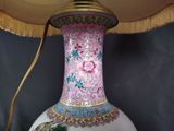 a pink and blue vase with a gold base and a lamp on it