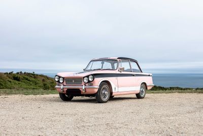 a pink car that is parked on the side of the road
